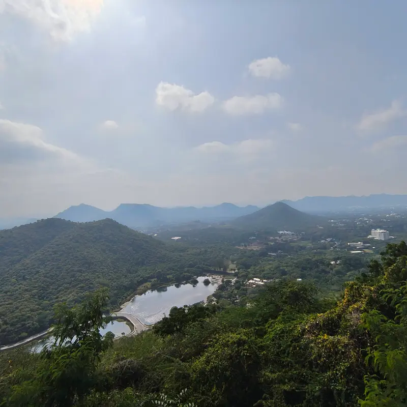 Green Aravalli hills and a small lake seen from a hilltop
