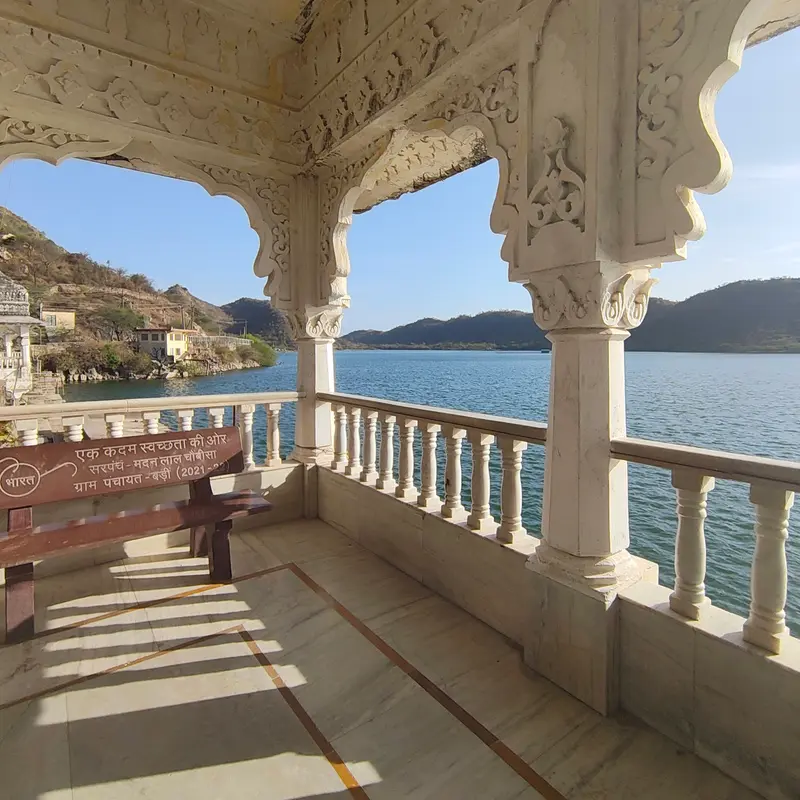 A carved marble pavilion looking out over a lake and hills